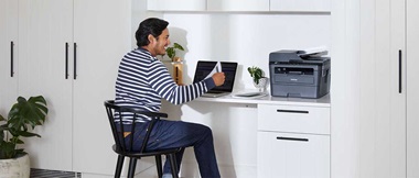 ragazzo lavoro da casa alla scrivania con pc e stampate Brother