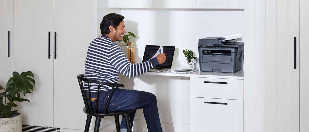 ragazzo lavoro da casa alla scrivania con pc e stampate Brother