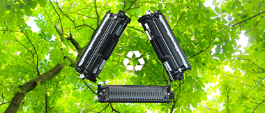 Recyclable Brother toner cartridges against a background of bright green tree leaves