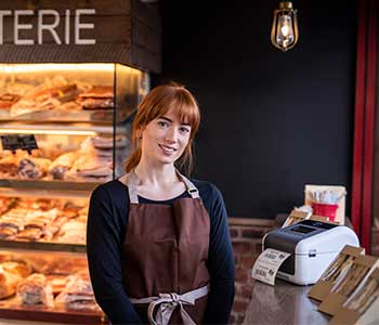 Donna in una caffetteria con stampante di etichette TD sul bancone