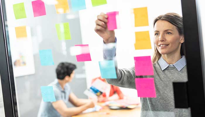 Donna che appoggia post-it a colori su un vetro