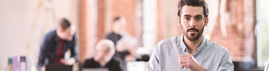Uomo in ufficio con persone sullo sfondo che parlano
