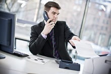 uomo utilizza fax nell'ufficio mentre telefona